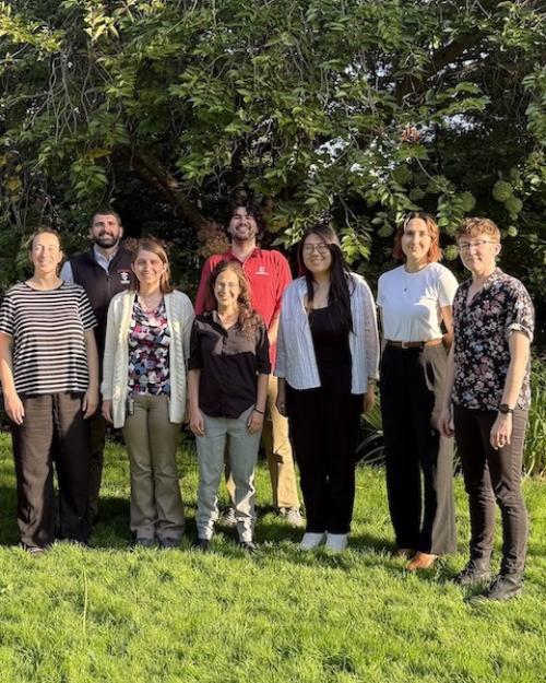 Nine people standing in a grassy area