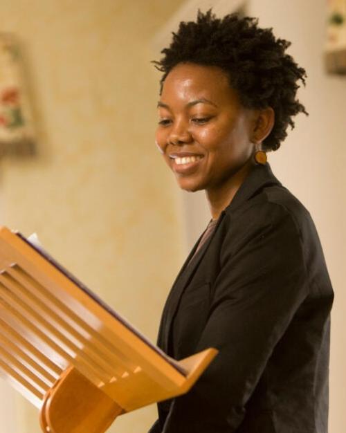 		Person standing at a small podium, smiling
	
