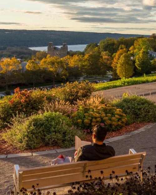 People reading on benches that overlook a grand view of a lake and autumnal trees