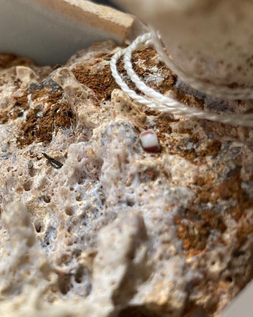 Lumpy, tawny, textured surface with one smooth bead embedded in it