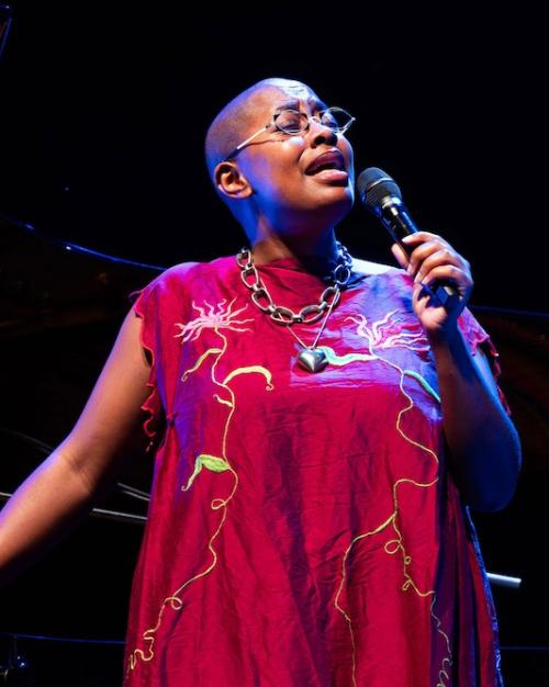 Person in a red dress, singing into a microphone