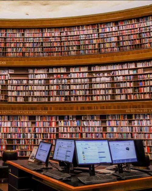 books in a library with computers on table