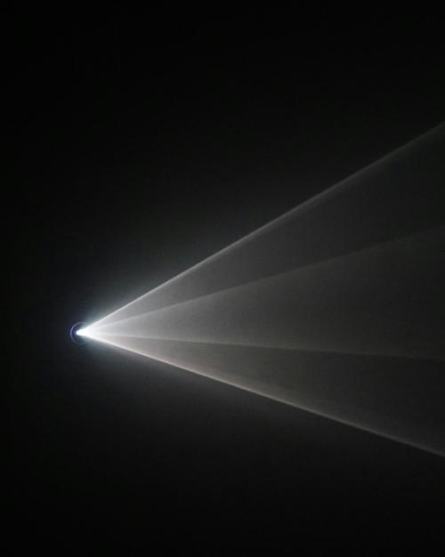 Light source sends white rays across a dark space
