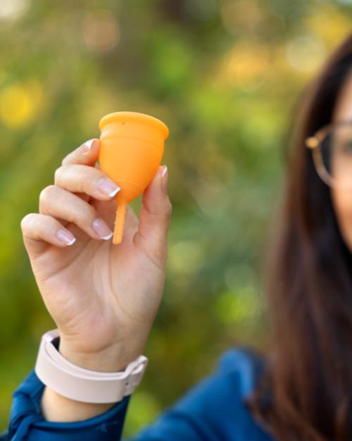 Person holding up an orange menstrual cup