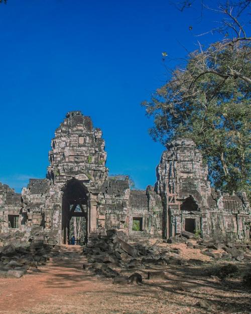 		ancient stone temple surrounded by trees, under a bright blue sky
	