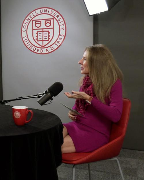 		Two people conversing at a black round table, talking into microphones
	