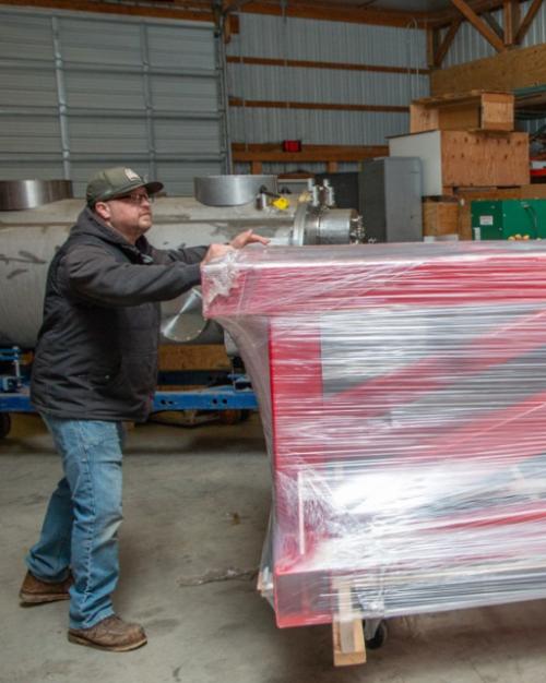 		Person pushing, on a dolly, a large red frame wrapped in plastic
	