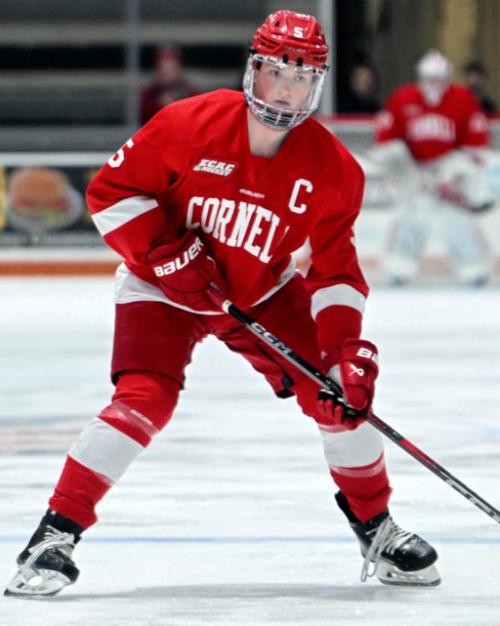 Person in red hockey gear, puck near the stick