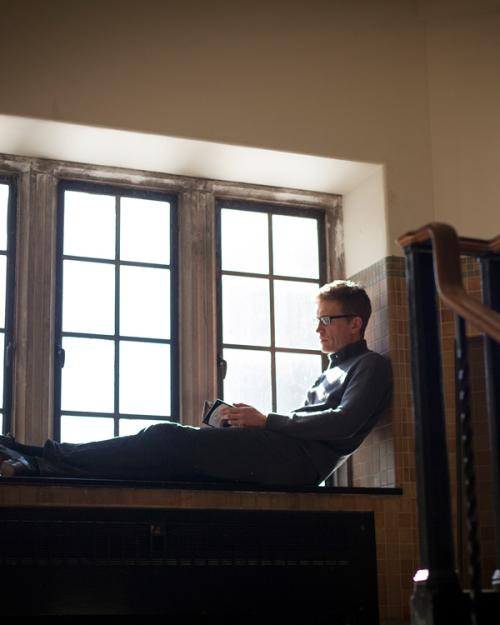 Person sitting in a deep windowsill, reading a book