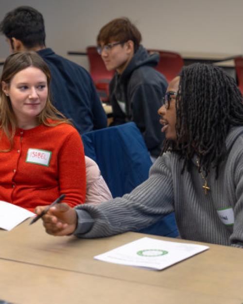 Students sit at tables, discussion together