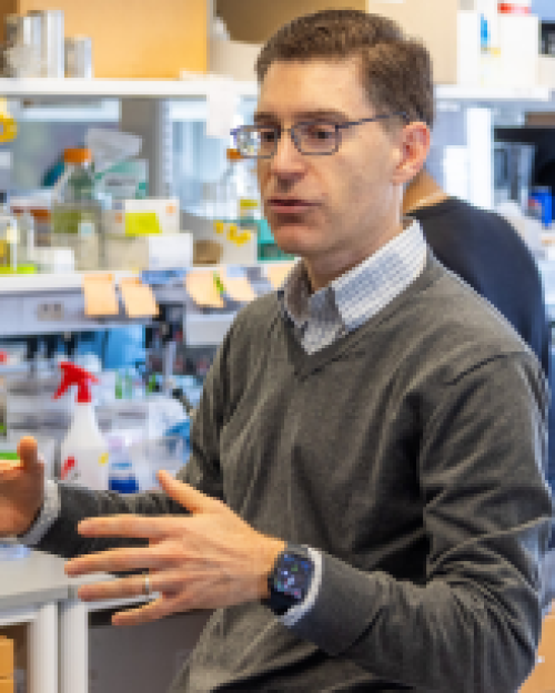Person talking with lab equipment in the background