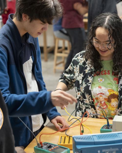 Two students connecting wires on a lab table