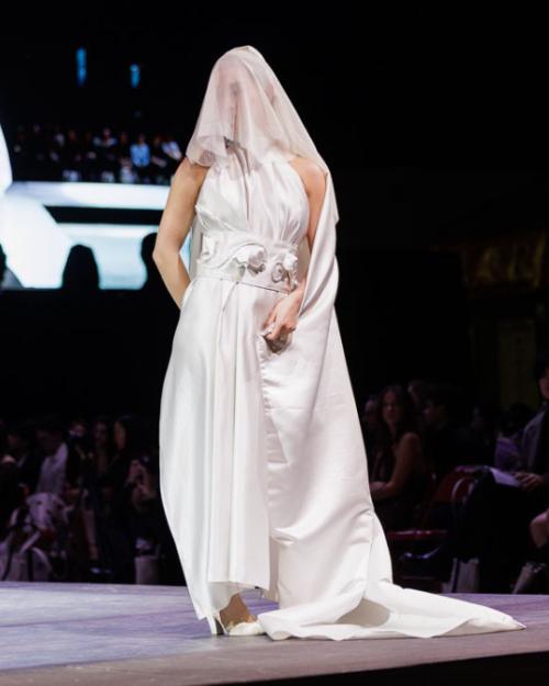 A person walking down a runway wearing a white dress