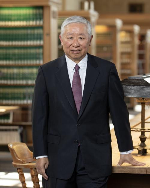 Person wearing a business suit stands in a law library with rows of book stacks behind him