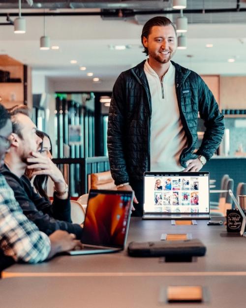 Person standing befor others, a computer open, looking confident