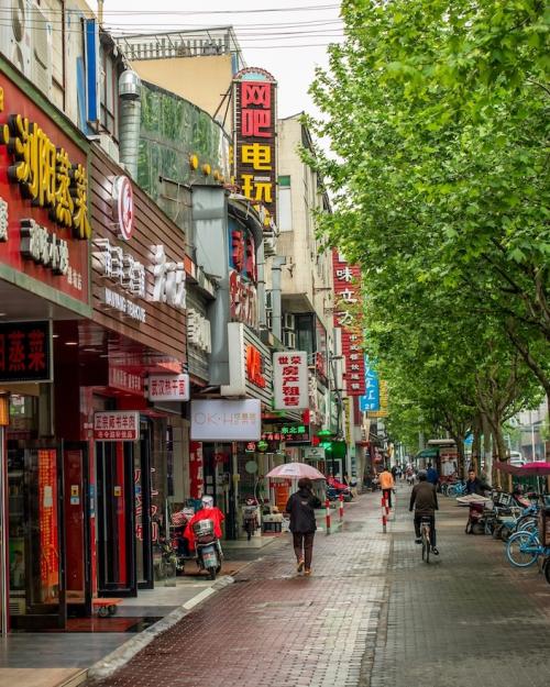 City street with people on a walkway and bright signs in Chinese lettering