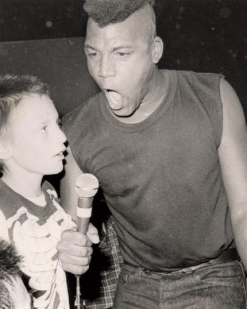 Black and white photo of a person hollering into a microphone with an intense look on his face
