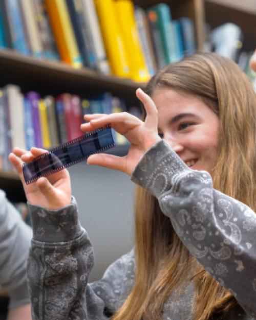 High school students smiling and looking at an old photo negative.