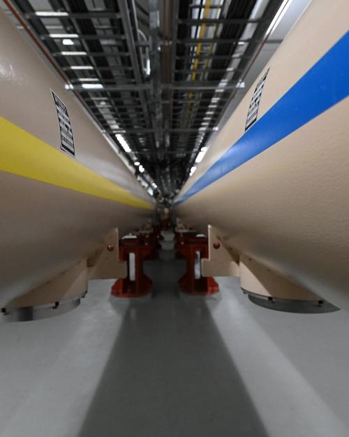 Close up of two very large tubes, the one on the left with a yellow stripe, the one on the right with a blue stripe