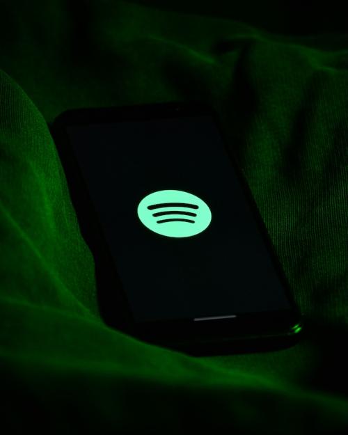 Green circle Spotify logo with black sound waves against a dark backgroun