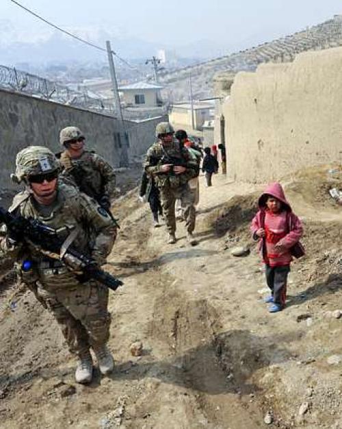 Armed soldiers walk up an incline alongside five children in colorful clothing. It's peaceful