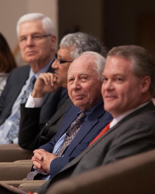 Five people sitting in chairs on a stage for an academic panel