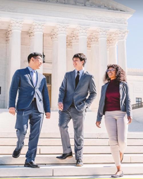 Three people on the steps of a building so white it glows