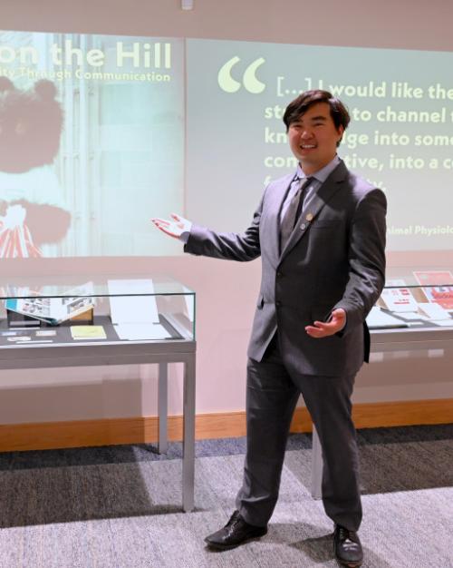 Person in suit presenting a display case and an image projected on a wall