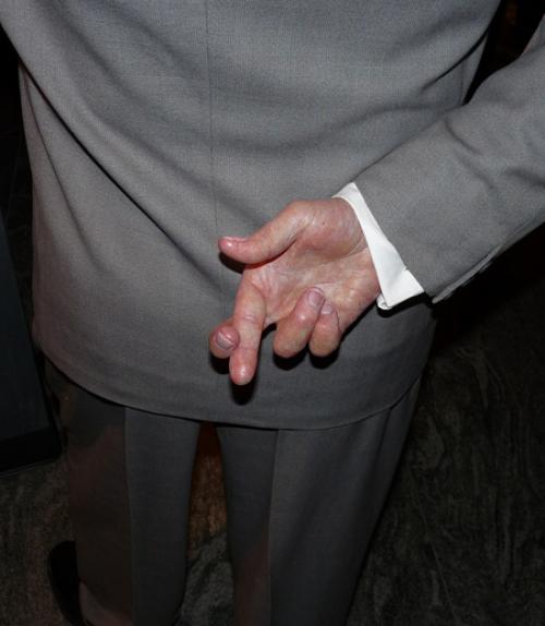  Man in business suit holding crossed fingers behind his back