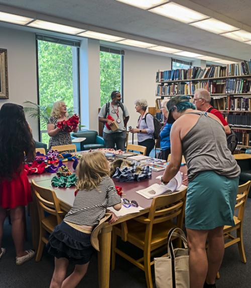  Alumni and families gather around a table with hyperbolic crochet examples and books