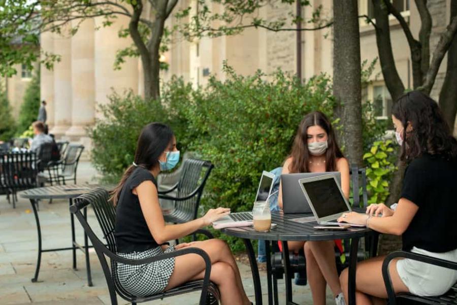 Masked students studying at a table outside of Goldwin Smith Hall
