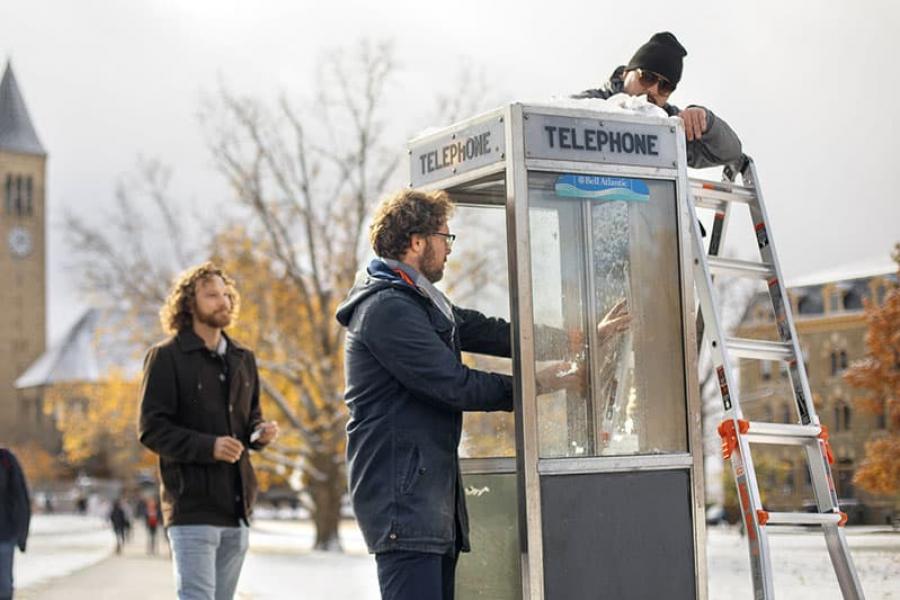 Sam Harnett, left and Hoff, right, install sound equipment in a phone booth on the Arts Quad, one of five “listening stations” installed around campus as part of the event