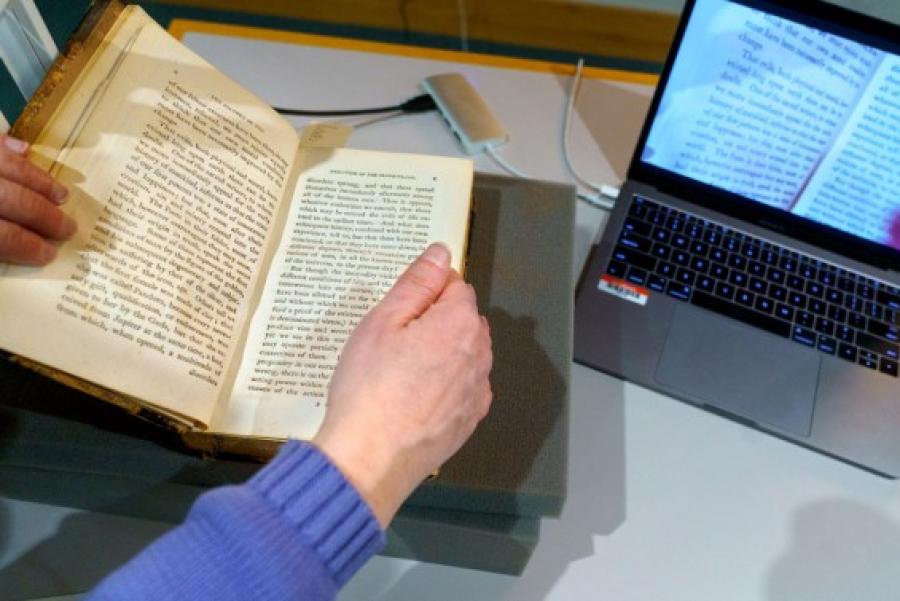 Hands holding a book near a computer screen