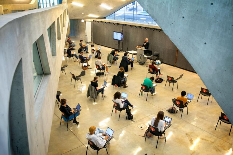 Students, sitting far apart, meet for class in Milstein Hall