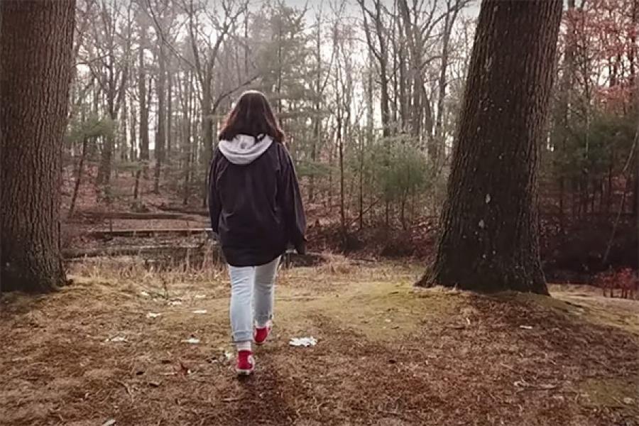 student walking through woods
