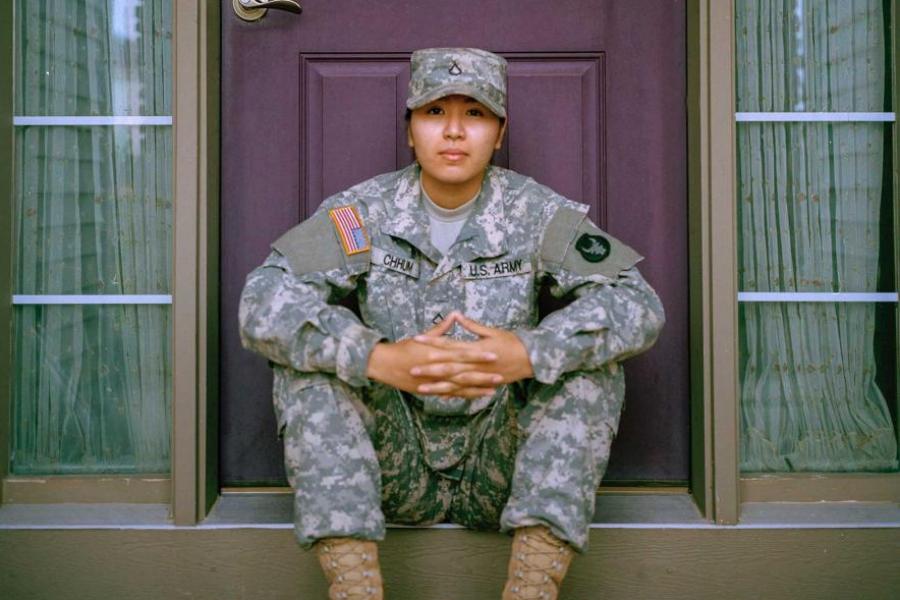 Person wearing fatigues sitting on a porch