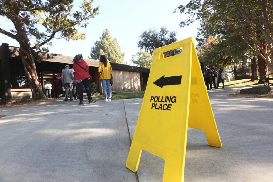 Yellow "polling place" sign and voters