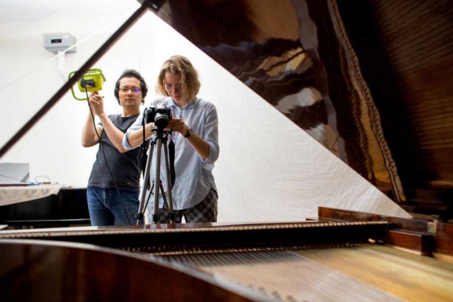 two people taking photos of a piano