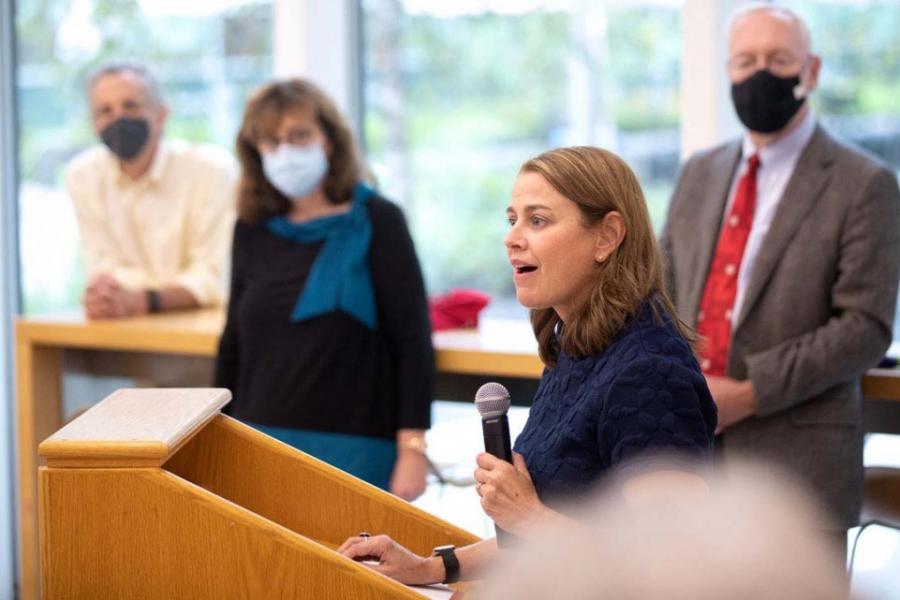 Dean Colleen Barry with microphone in hand, speaking at podiumSchool of Public Policy