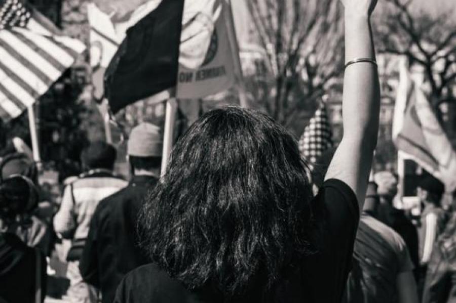 A woman standing with her fist upraised at a protest at the White House