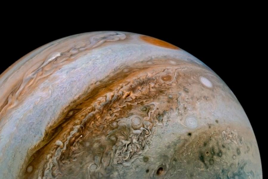 Jupiter with bands of swirling color and a red spot at top of sphere.
