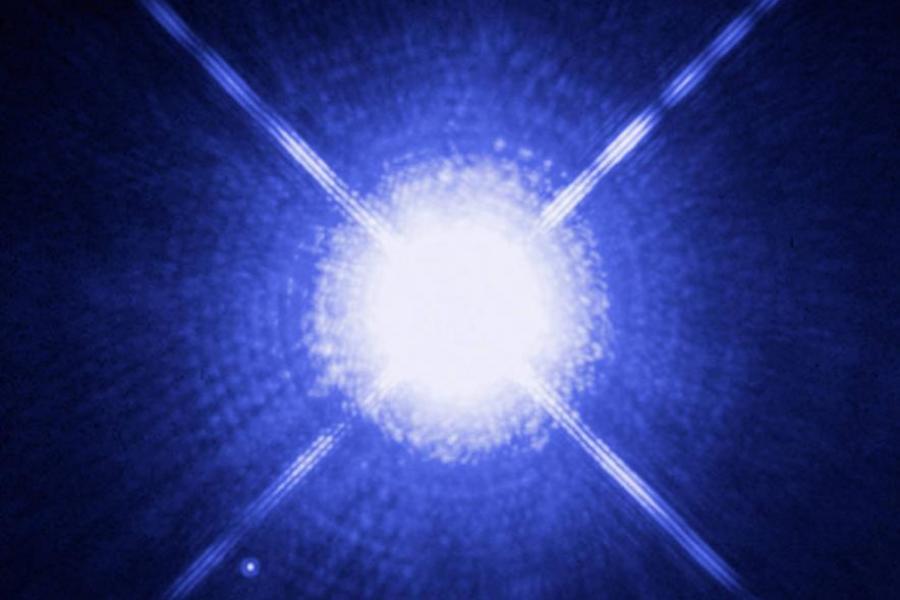 Four lines of light radiating out from a white dwarf star on a blue background.