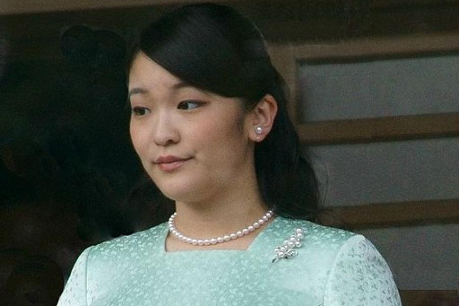 Princess Mako wearing pearl earrings, necklace and pin, and a long sleeved green dress; she is holding white gloves and a fan. 