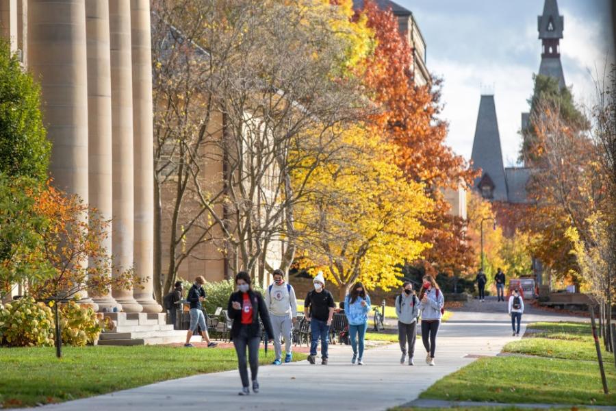 Students walking in front of Goldwin Smith Hall, with trees showing Autumn colors