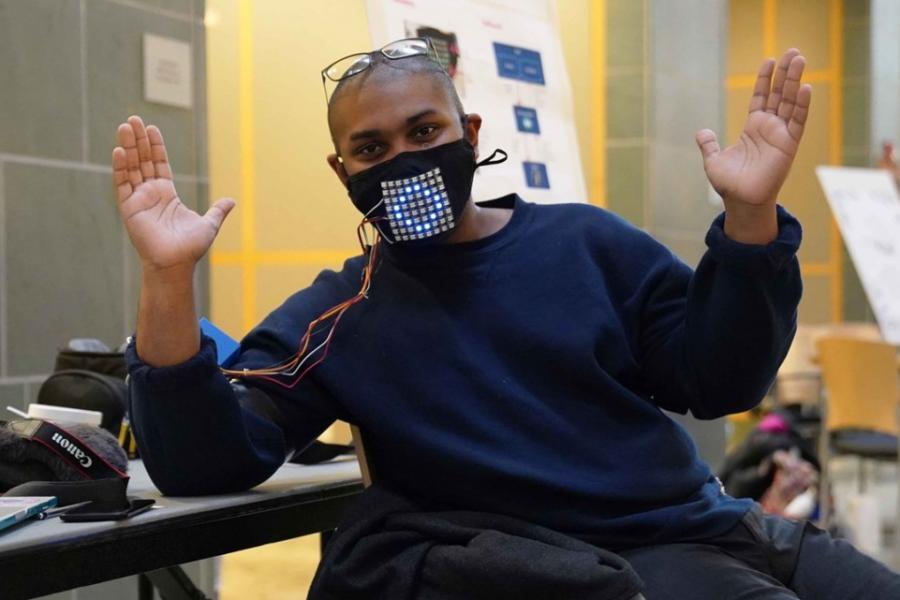 Person wearing a black face mask with silver grid on it