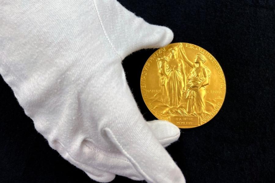 Gloved hand holding a gold medal