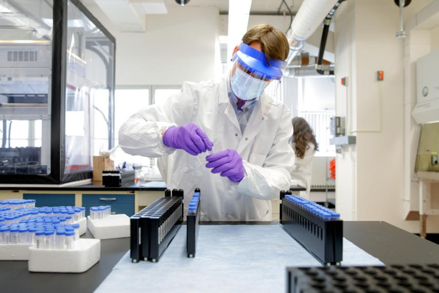 Person wearing protective lab gear handles virus test samples