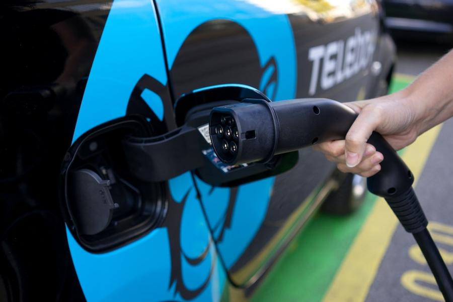 Hand holding electric charger to car