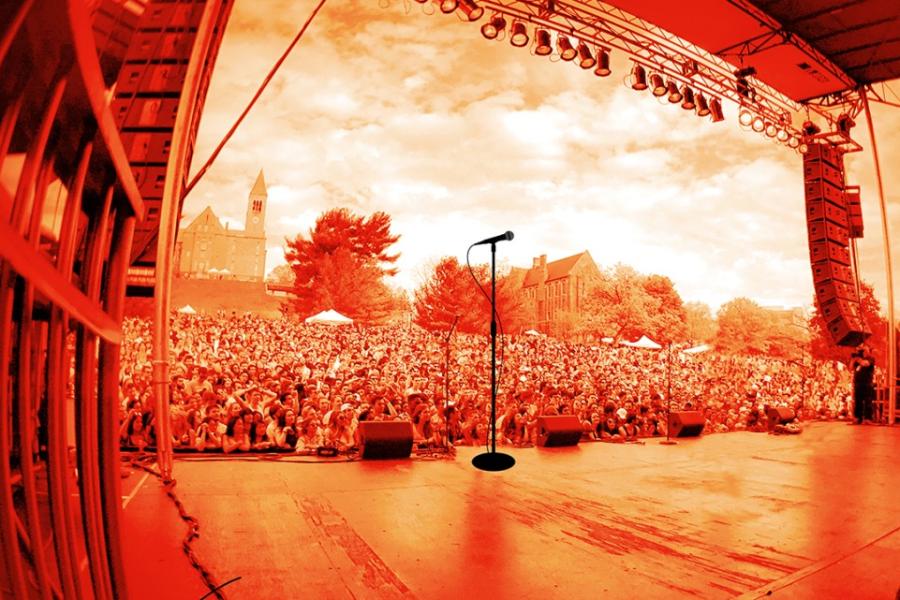 Red-tinted image of a stage from the performers point of view, looking out at a large crowd outside