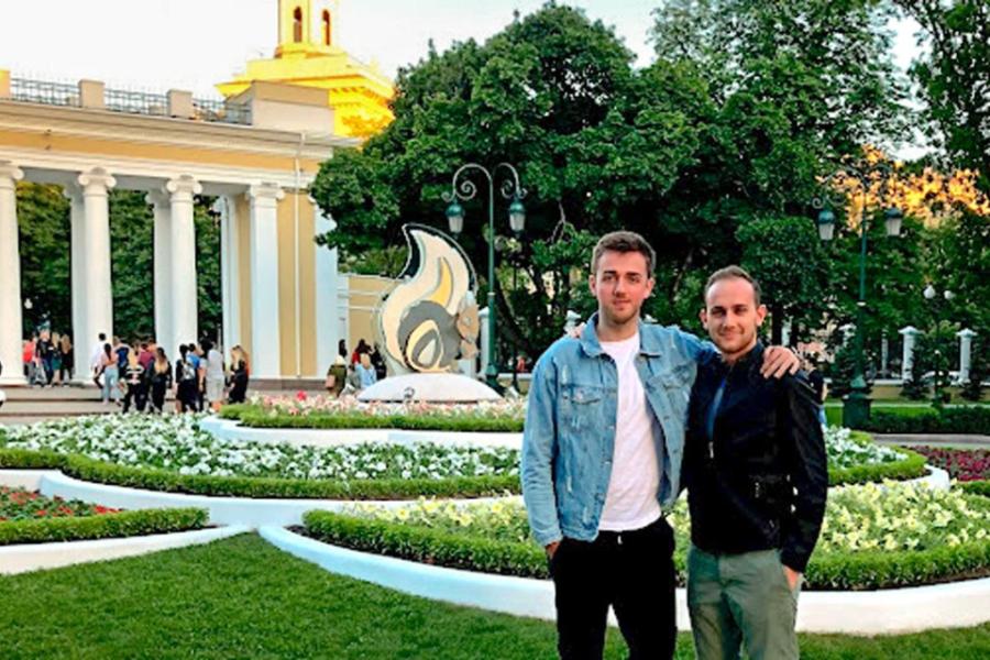 Two people stand side by side in a formal garden